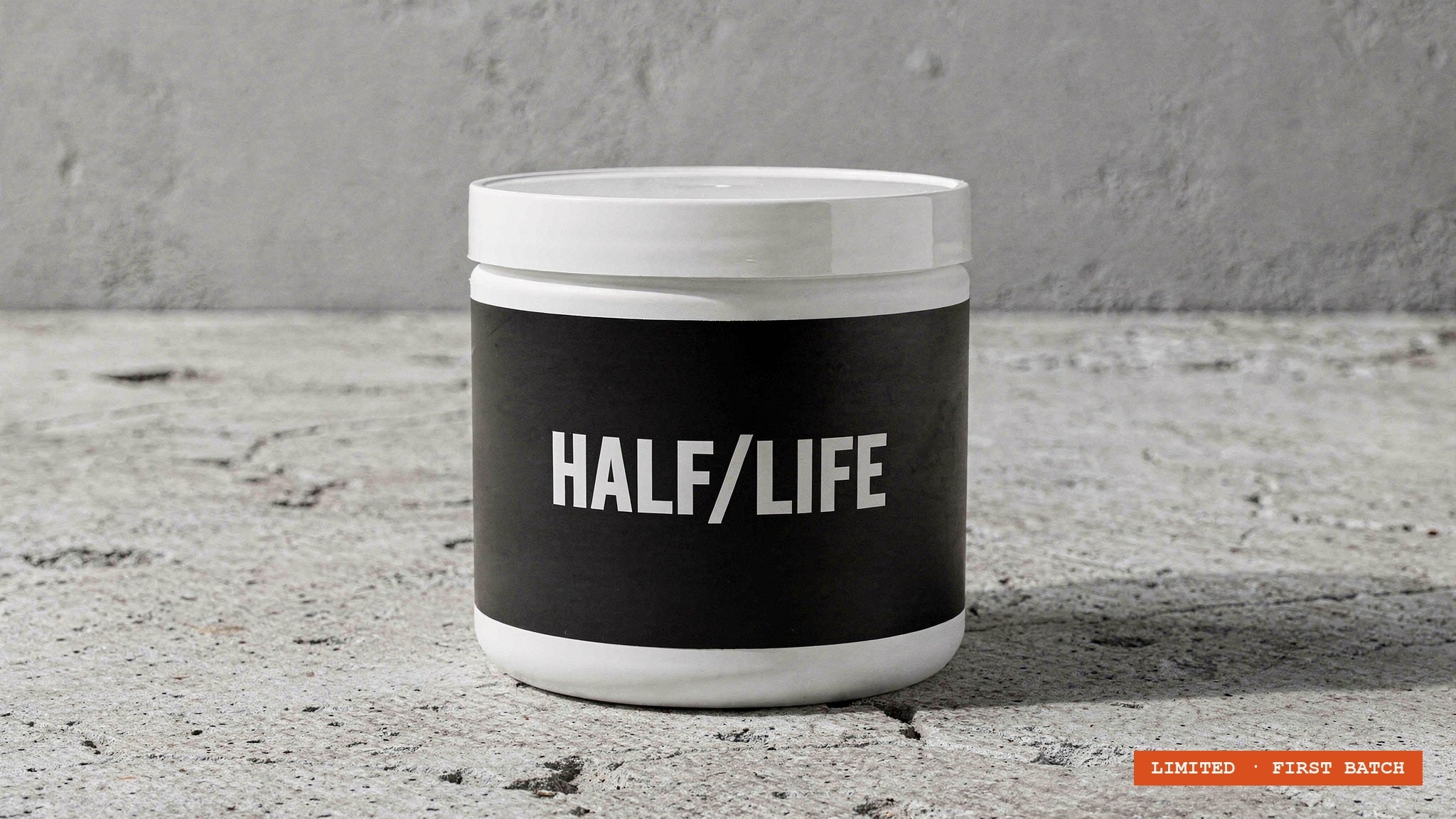 HALF/LIFE creatine tub on a paper-white backdrop with a small pile of creatine powder, documentary studio photograph